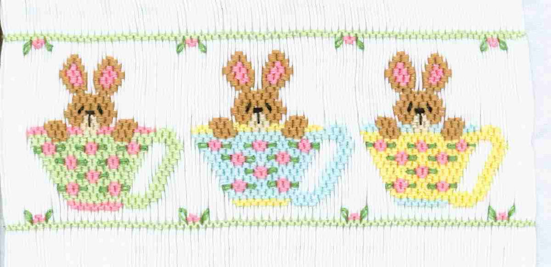 Smocking design of bunnies in teacups with floral designs on a white background