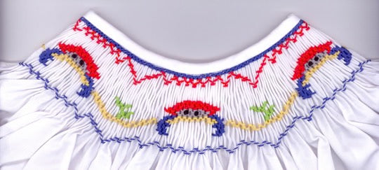 Close-up of a white garment with colorful embroidery on a gray background