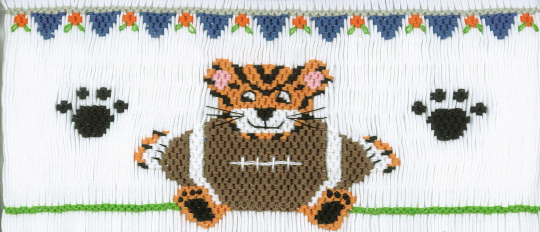 Smocking plate with tiger holding a large football and two paw prints. 9 3/4 rows of smocking on a yoke.
