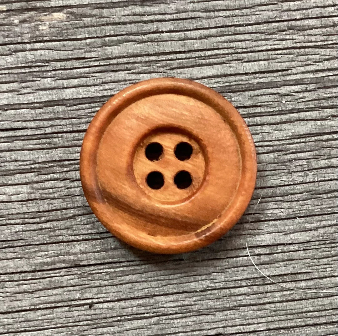 Wooden button with four holes on a wooden surface
