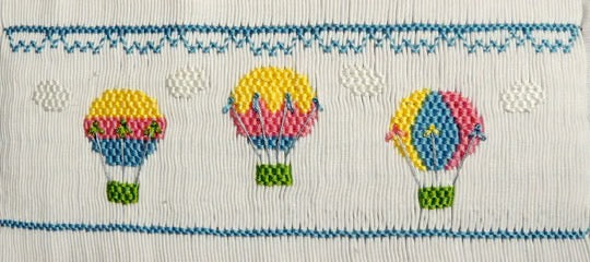 Smocking plate with three hot air balloons in the clouds. 8 rows of smocking on a yoke.