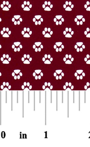 Fabric with white paw prints on a red background, measured by a ruler.