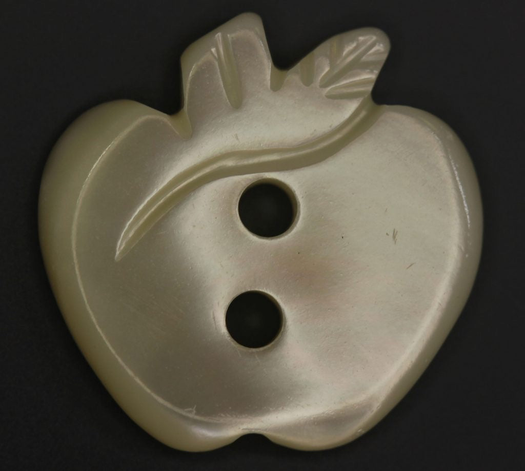 Decorative button shaped like an apple on a black background