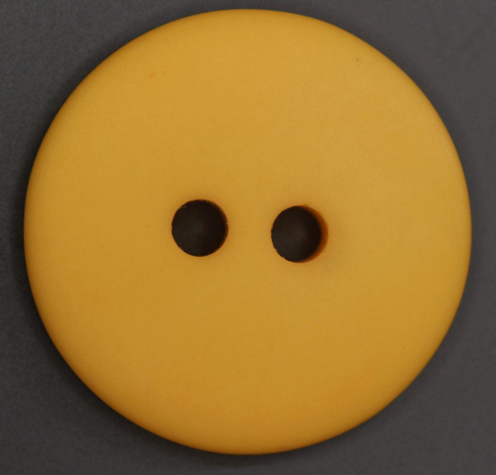 Yellow button with two holes on a dark gray background