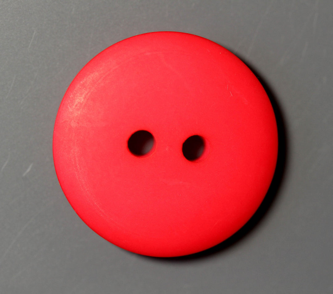 Red button with two holes on a gray background