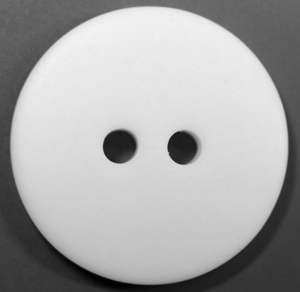 White button with two holes on a dark gray background