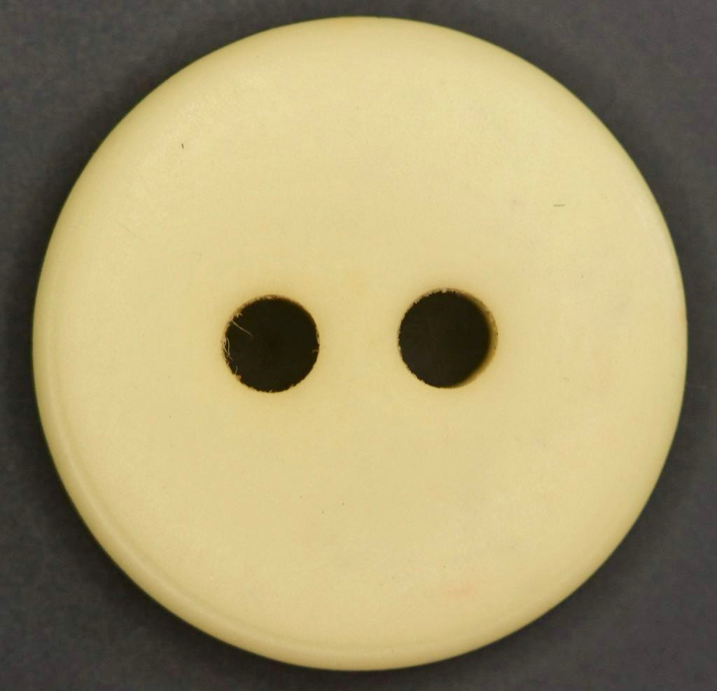yellow button with 2 holes on a dark background