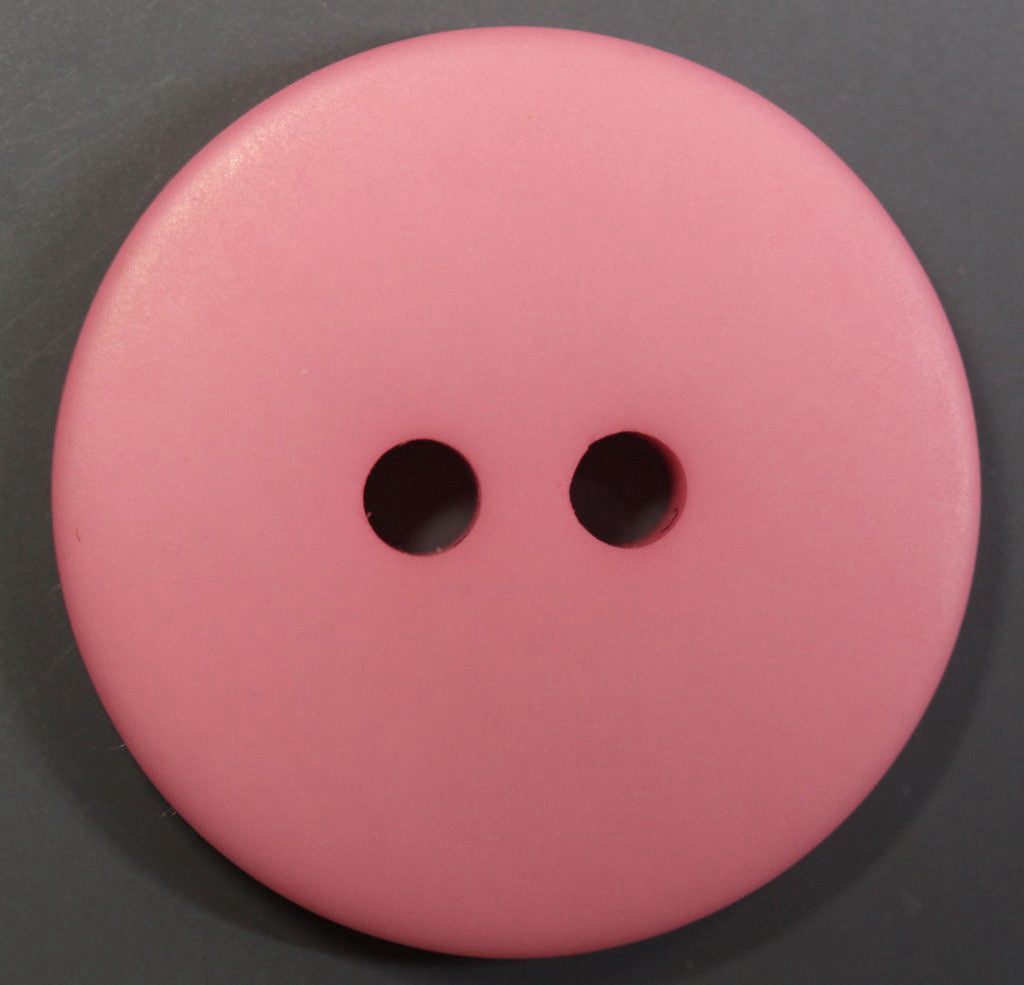 Pink button with two holes on a dark gray background