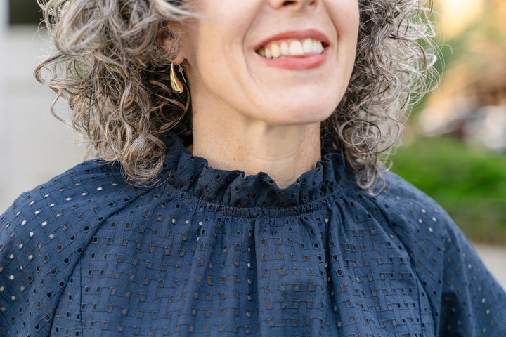 Woman wearing a blue blouse with a blurred outdoor background