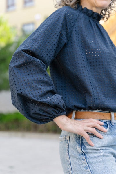 Person wearing a blue blouse with puffed sleeves and jeans outdoors