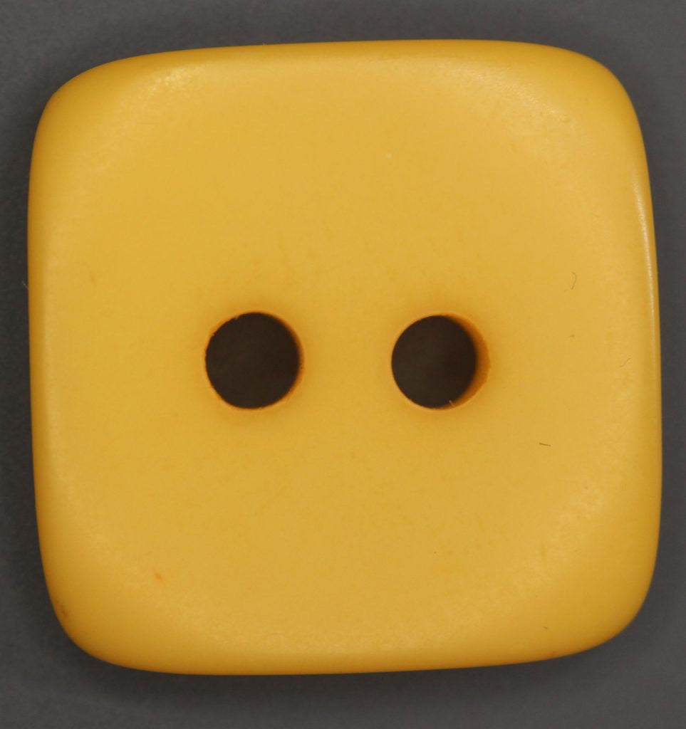 Yellow square two hole button on a dark background