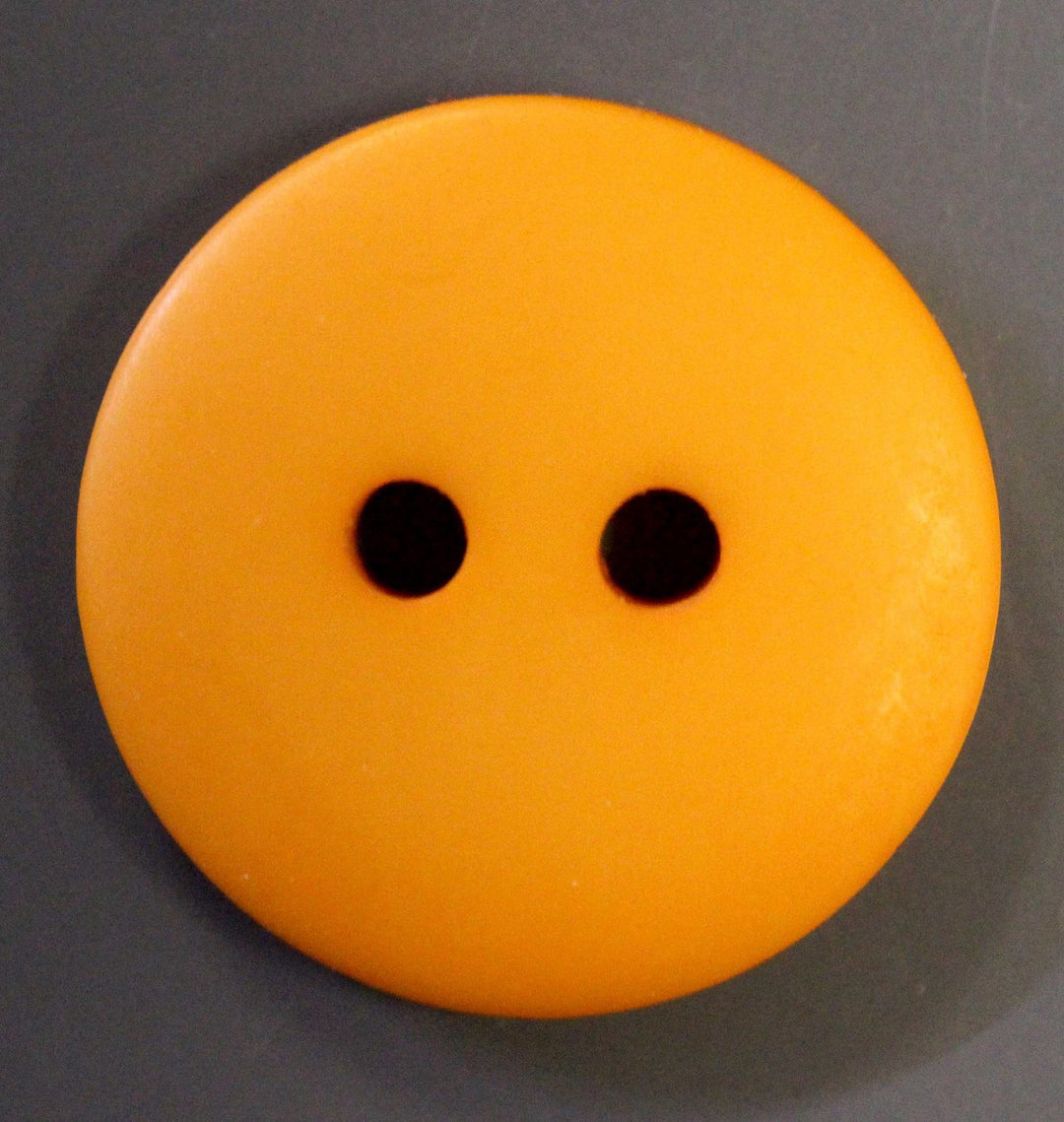 Orange 2 hole button on a gray background