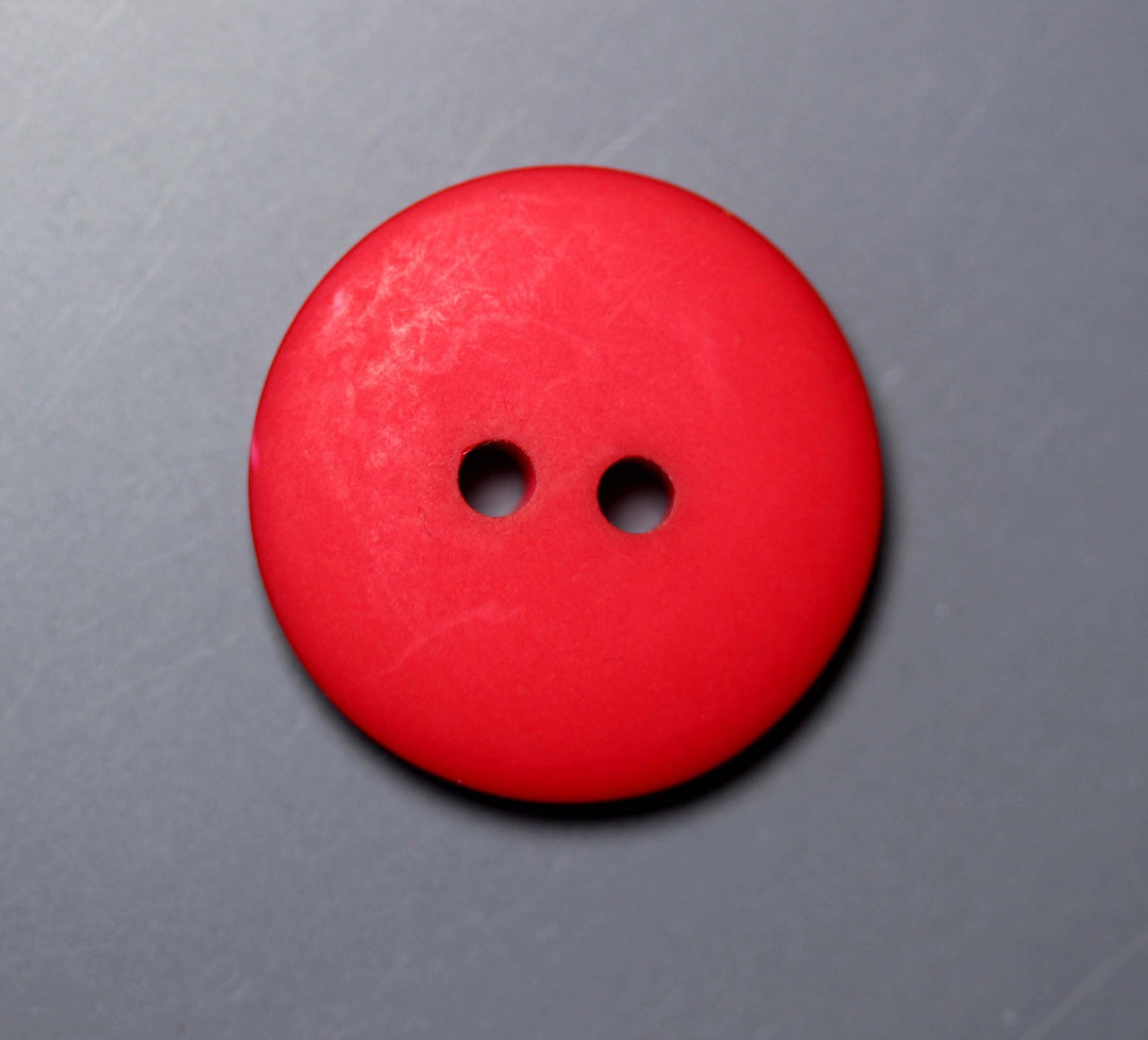 Red button with two holes on a gray background