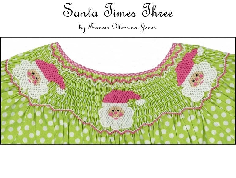A close-up of a green and white polka dot garment with a pink and white smocked yoke featuring three smocked Santa faces. 
