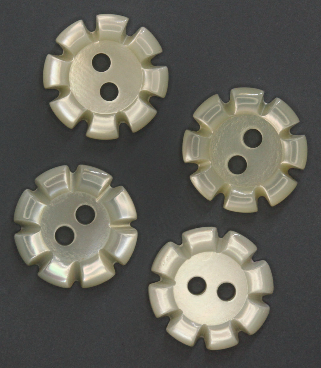 Four pearl buttons on a dark gray background