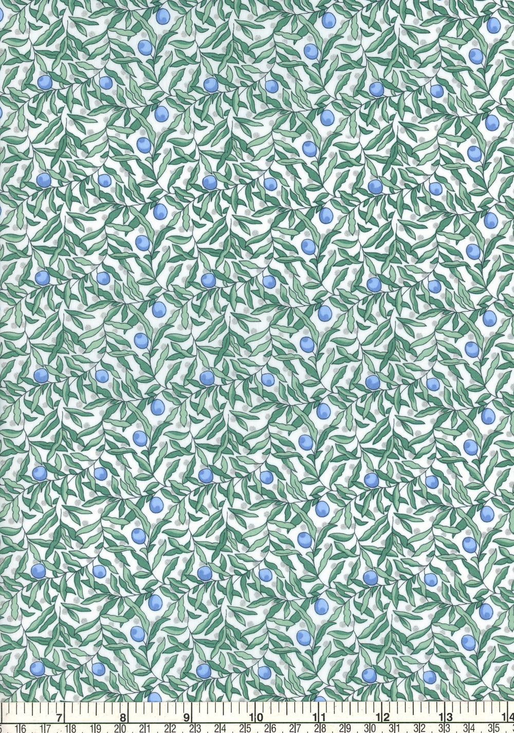 Fabric with green leaf pattern and blue berries on a white background, ruler at the bottom for scale.