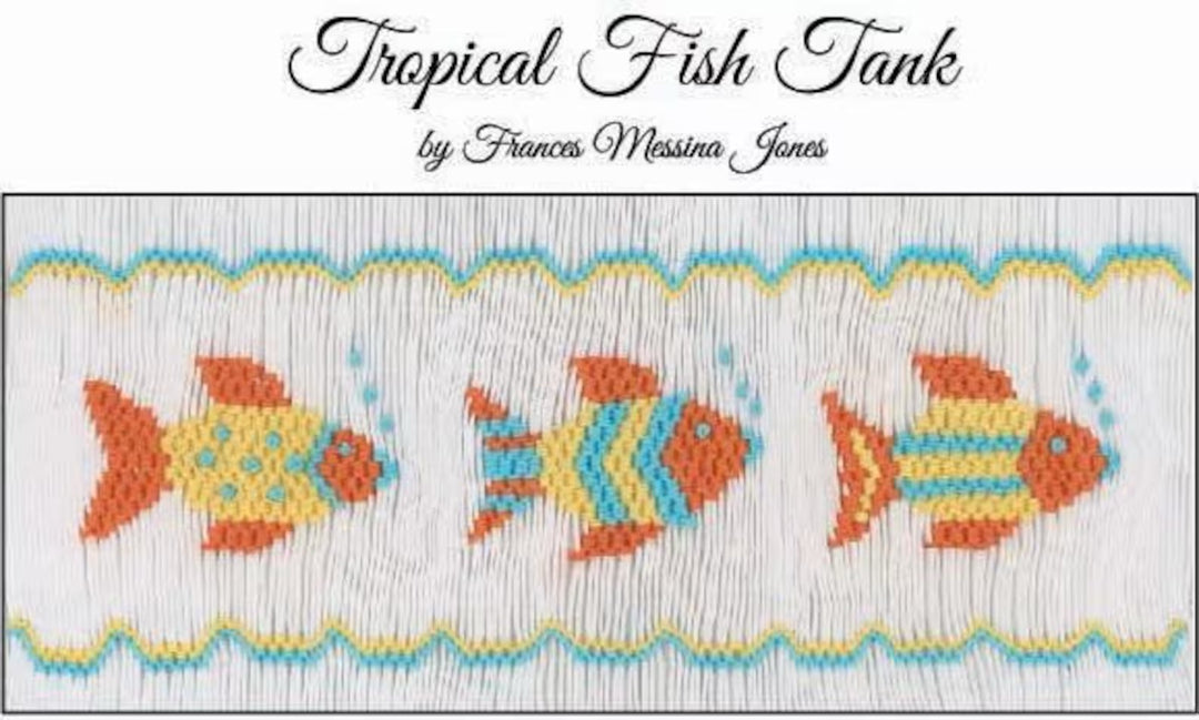 A smocking plate titled 'Tropical Fish Tank' by Frances Messina Jones, featuring three stylized orange and yellow fish with blue accents on a white stitched background with decorative wavy borders.