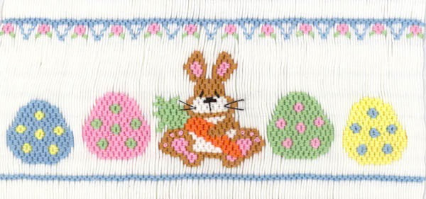 Smocking plate with a rabbit holding a carrot between eggs. 8 1/2 rows of smocking on a yoke.