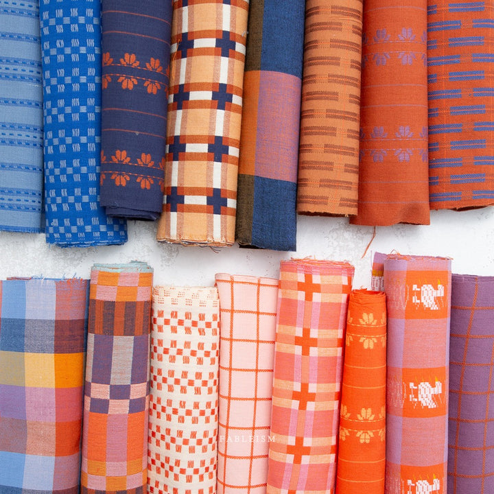 Collection of colorful fabric rolls with various patterns on a white background