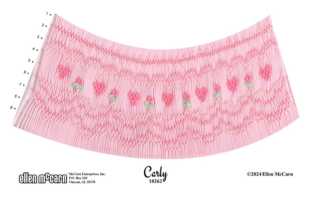 9 rows of geometric smocking  in pink and green with alternating tiny hearts and flowers in the middle row on pink pleated fabric