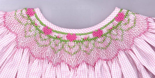 Close-up of a pink dress with floral embroidery on a gray background