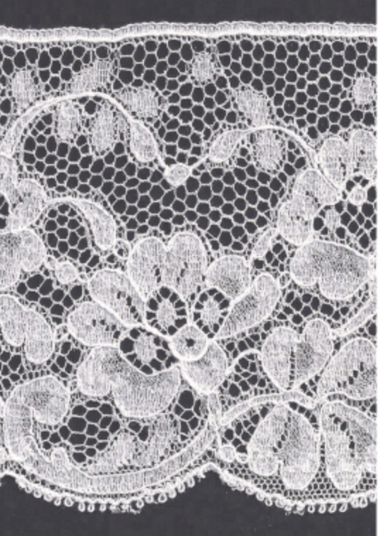 White floral lace trim with a scalloped edge, shown flat against a dark background.