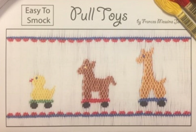 A close-up of a smocking plate labeled 'Pull Toys' with three toy figures on a white canvas: a yellow duck, a brown llama, and an orange giraffe.