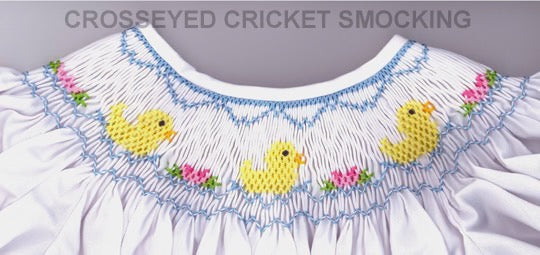 White garment with yellow duck and floral smocking detail on a gray background