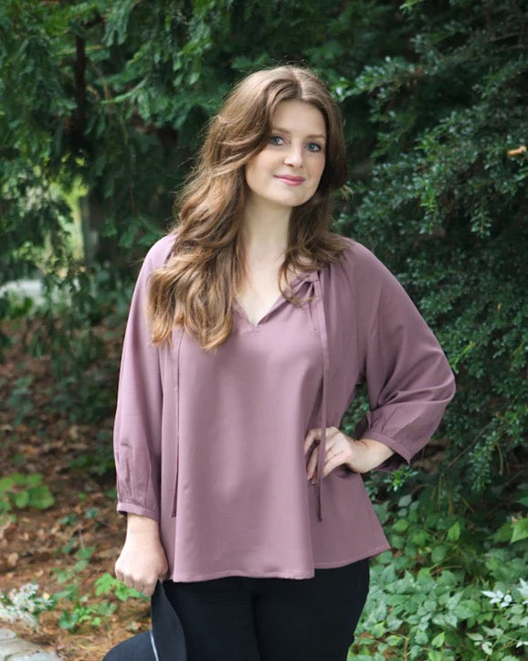 picture of girl with mauve top and black pants in front of a tree