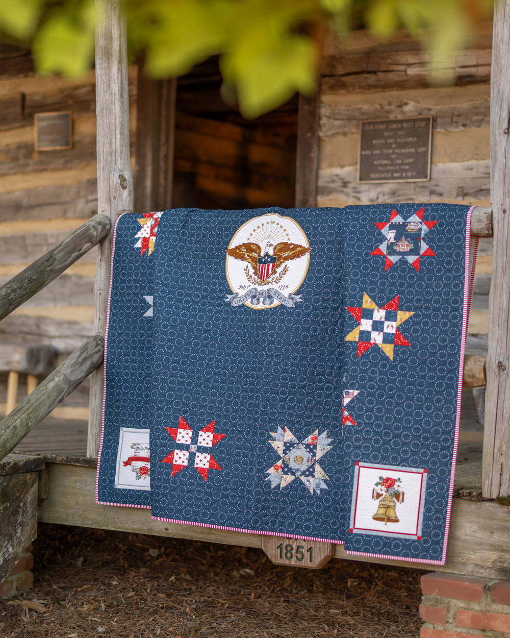 Quilt with patriotic designs draped over a wooden structure.