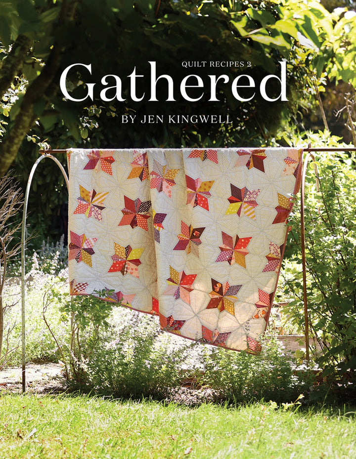 Quilt with colorful pattern hanging outdoors, featuring the title 'Gathered' by Jen Kingwell.