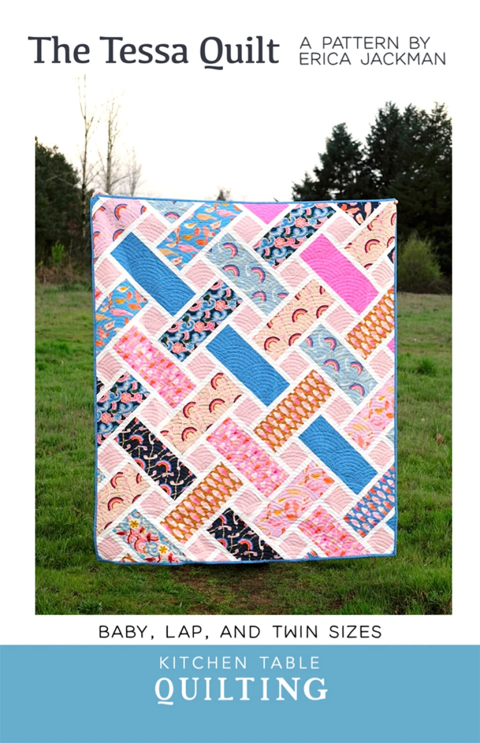Colorful quilt with geometric pattern on grassy field, 'The Tessa Quilt' by Kitchen Table Quilting.