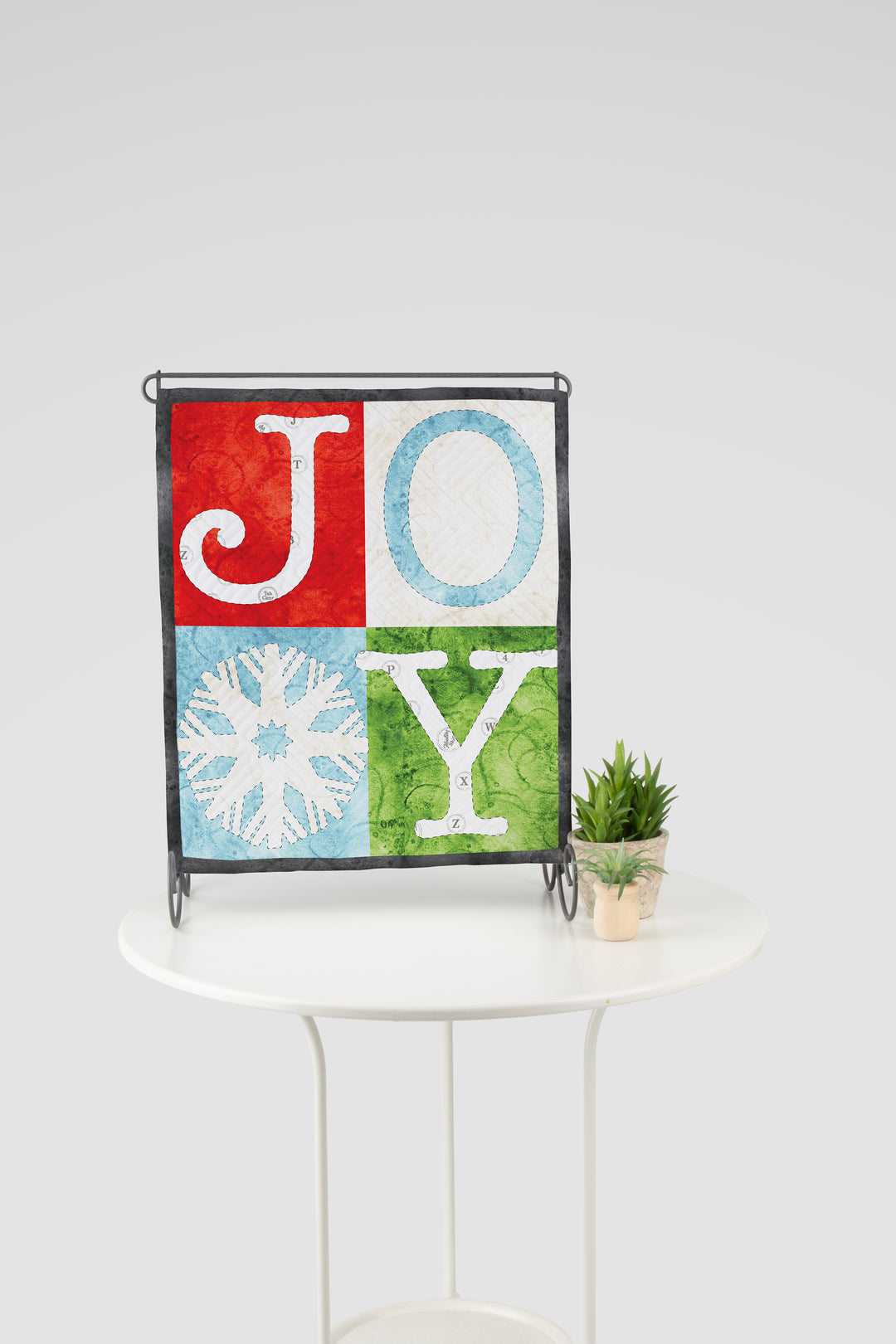 Decorative wall hanging with 'JOY' letters on a white table