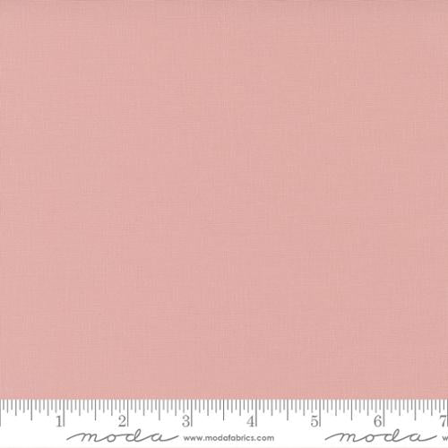 Pink fabric swatch with a ruler at the bottom for scale, featuring the Moda Fabrics logo.