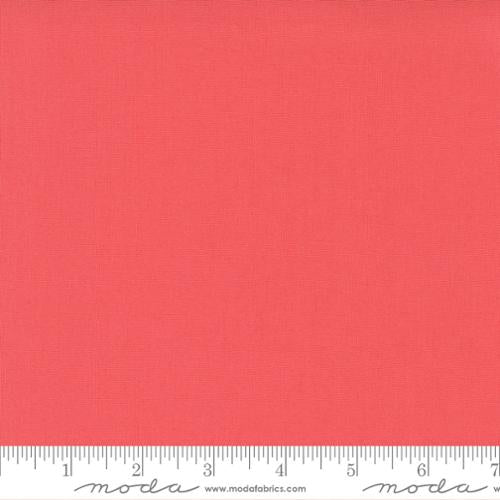 Solid coral fabric swatch with a ruler at the bottom for scale.