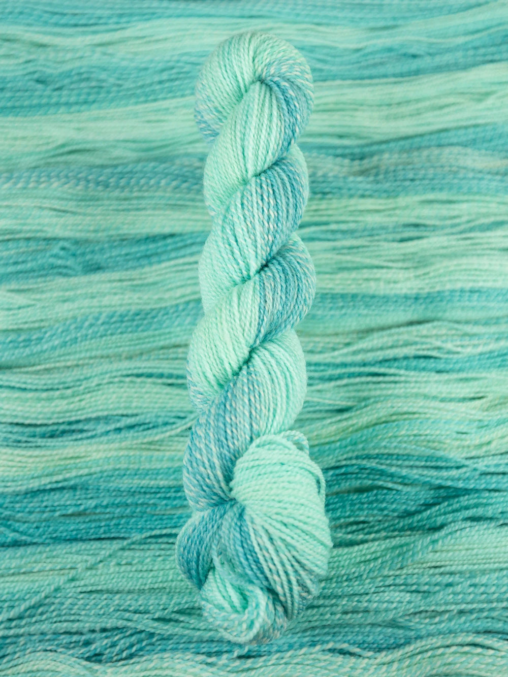 Turquoise skein of yarn on a textured teal background