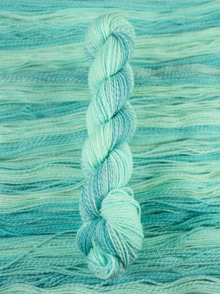 Turquoise skein of yarn on a textured teal background