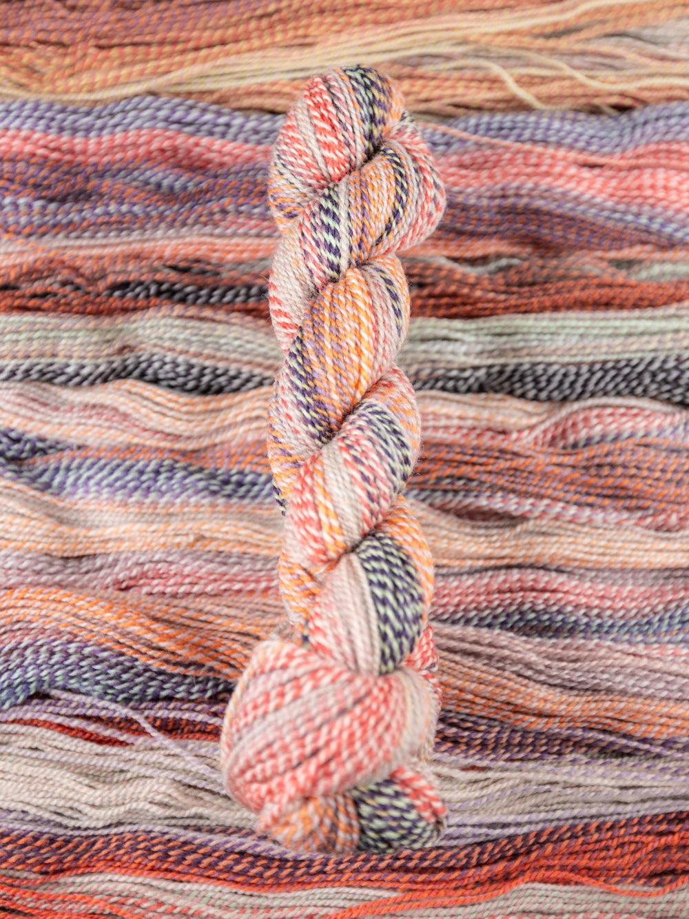 Multicolored skein of yarn on a woven fabric background