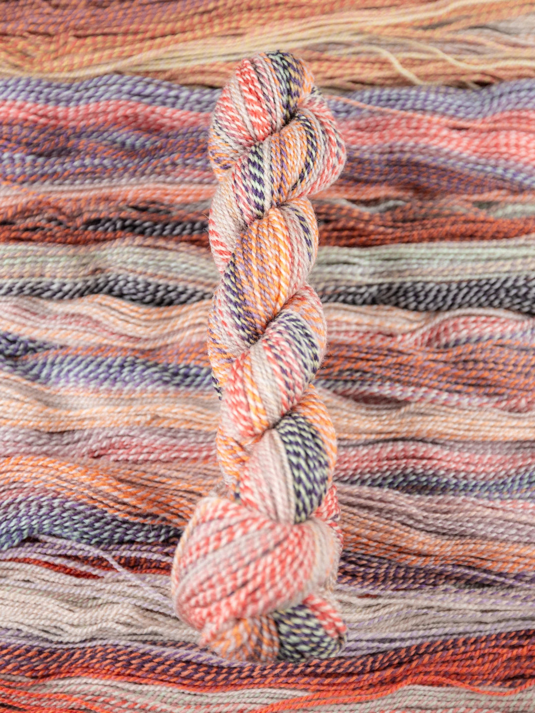 Multicolored skein of yarn on a woven fabric background