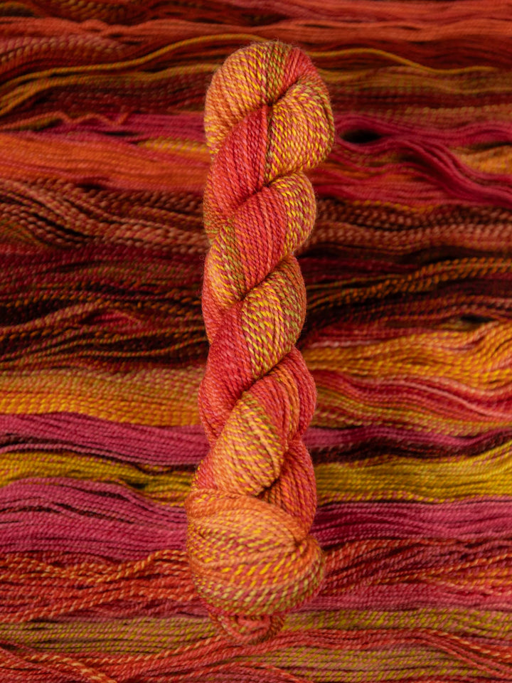 Colorful skein of yarn on a textured orange and pink fabric background