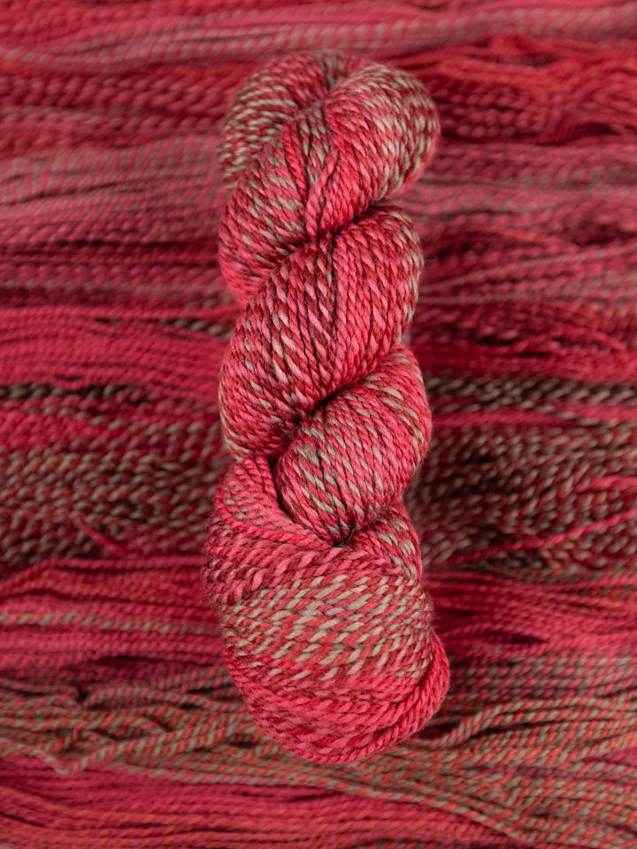 Red skein of yarn on a textured red fabric background