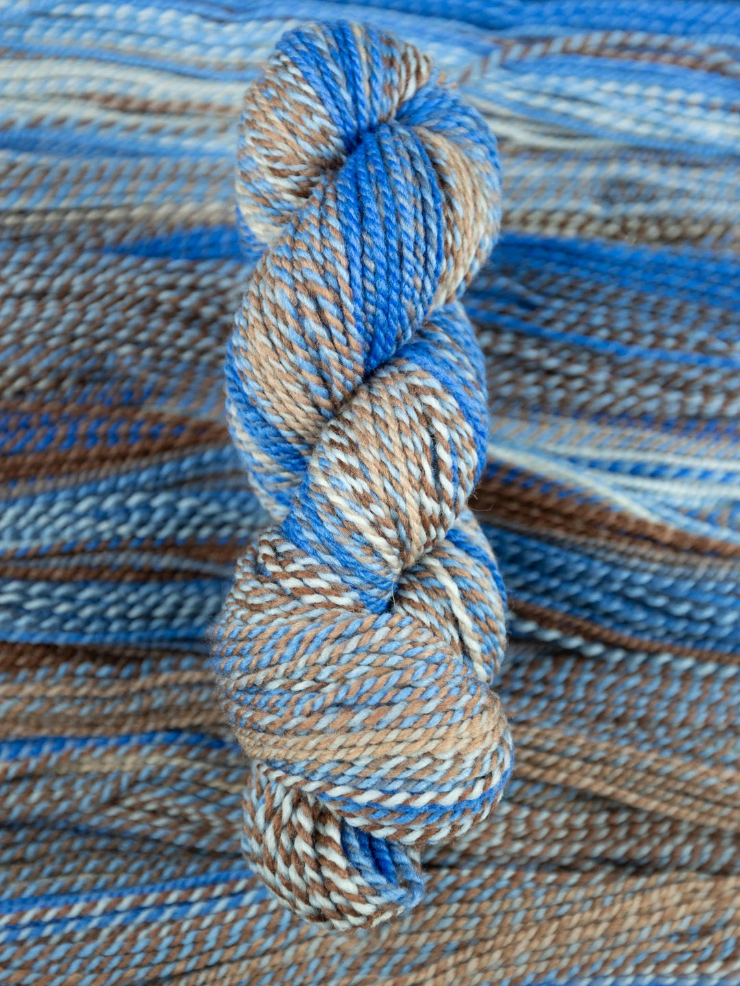 Close-up of blue and brown yarn skein on a textured fabric background