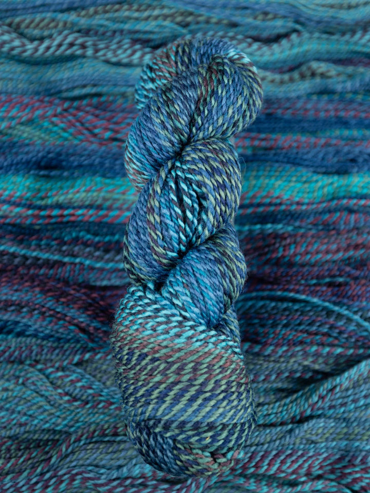 Blue and purple skein of yarn on a textured fabric background
