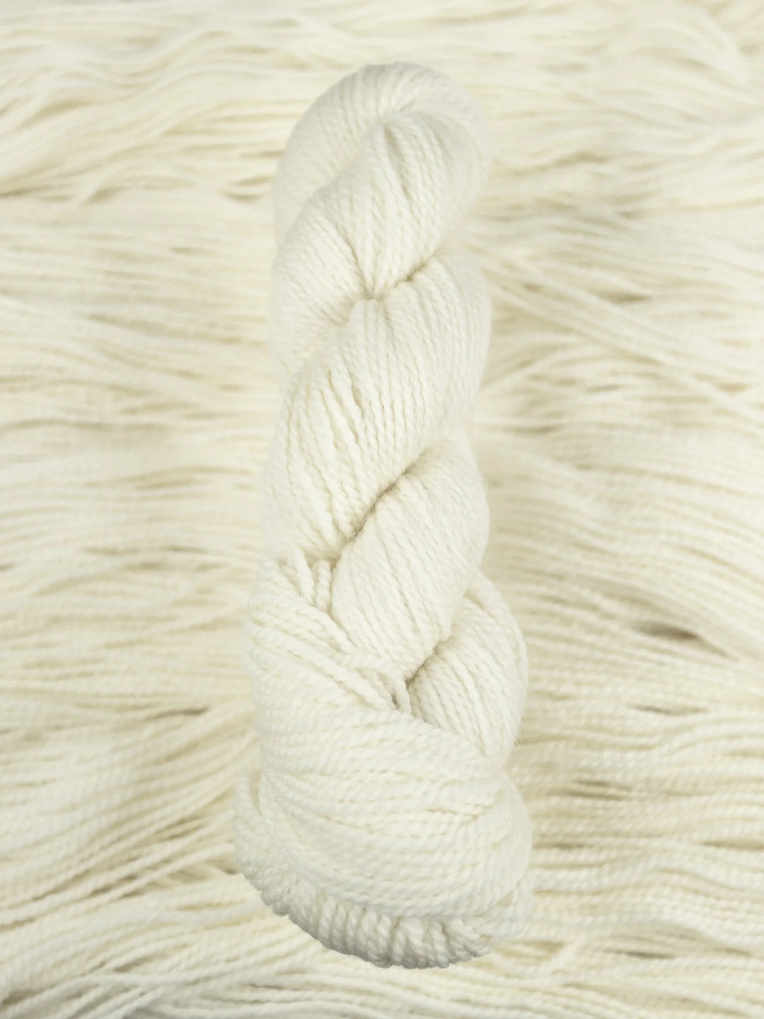 Close-up of a skein of white yarn on a textured beige background