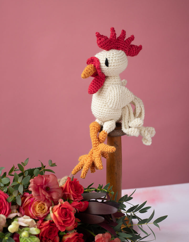 Finished Matthew the Leghorn Cockerel product posed on a perch with flowers below