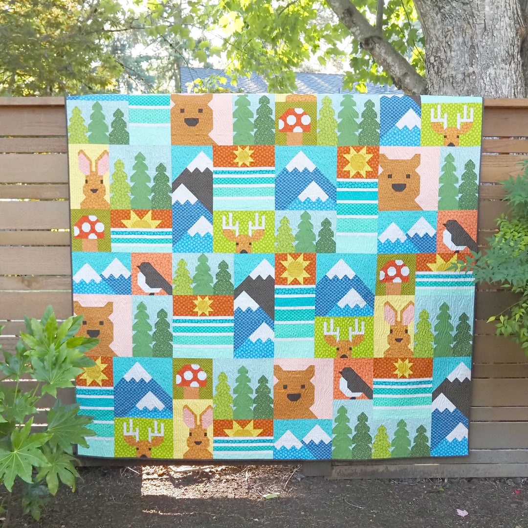 Colorful quilt with nature-themed patterns displayed outdoors.