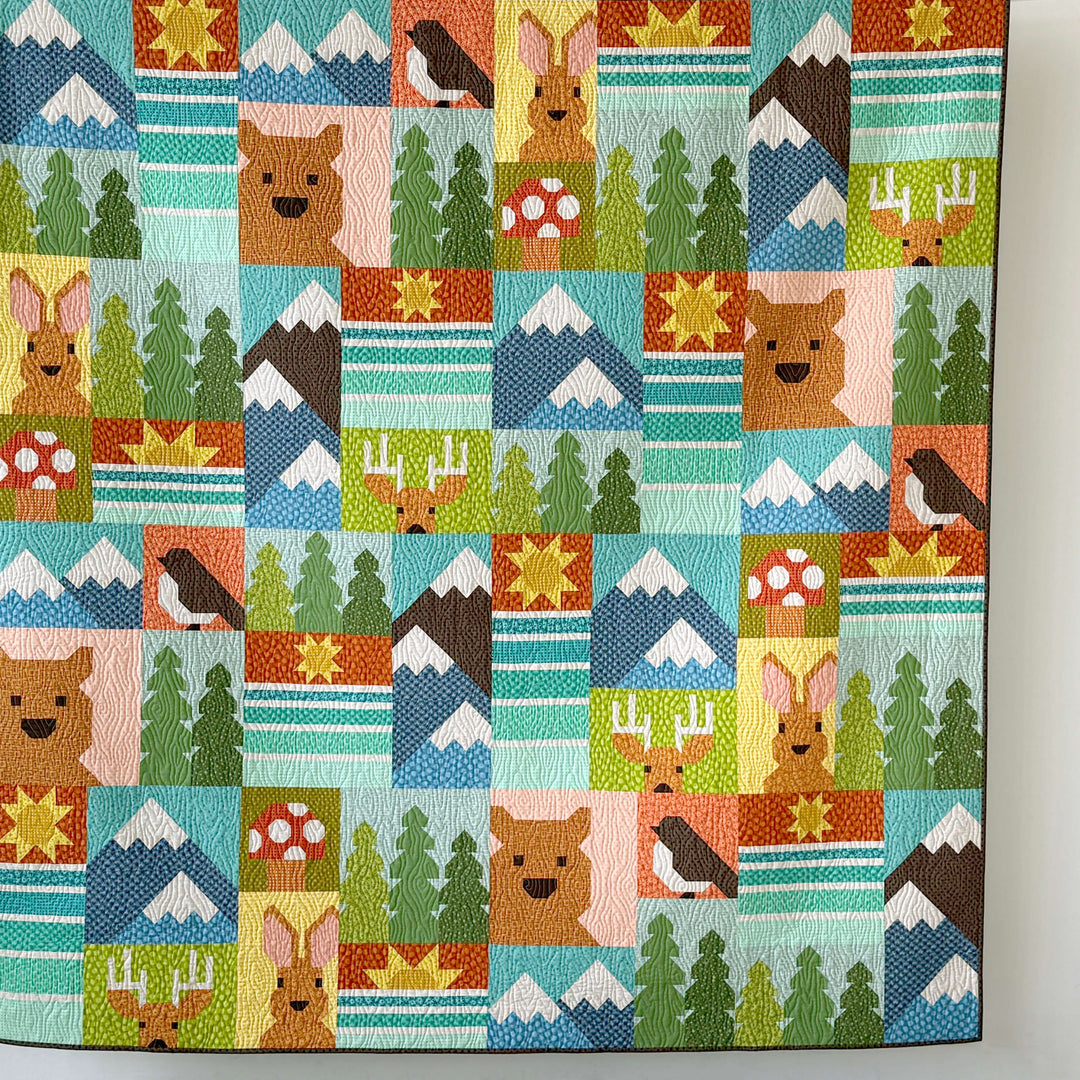 Colorful quilt with nature-themed blocks featuring animals and landscapes.