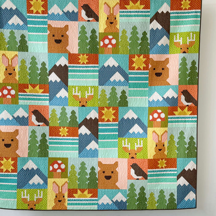 Colorful quilt with nature-themed blocks featuring animals and landscapes.