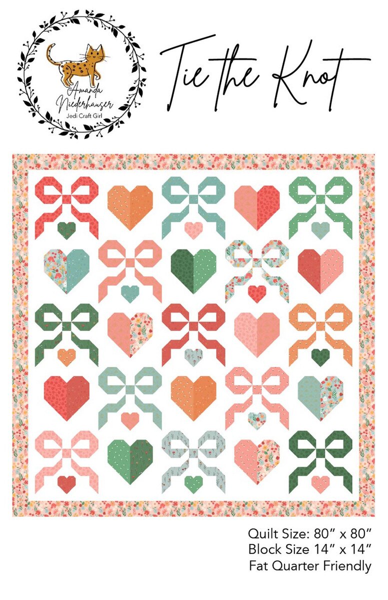 Quilt pattern of bows and hearts  in pink, red, blue and green, with a floral border. 