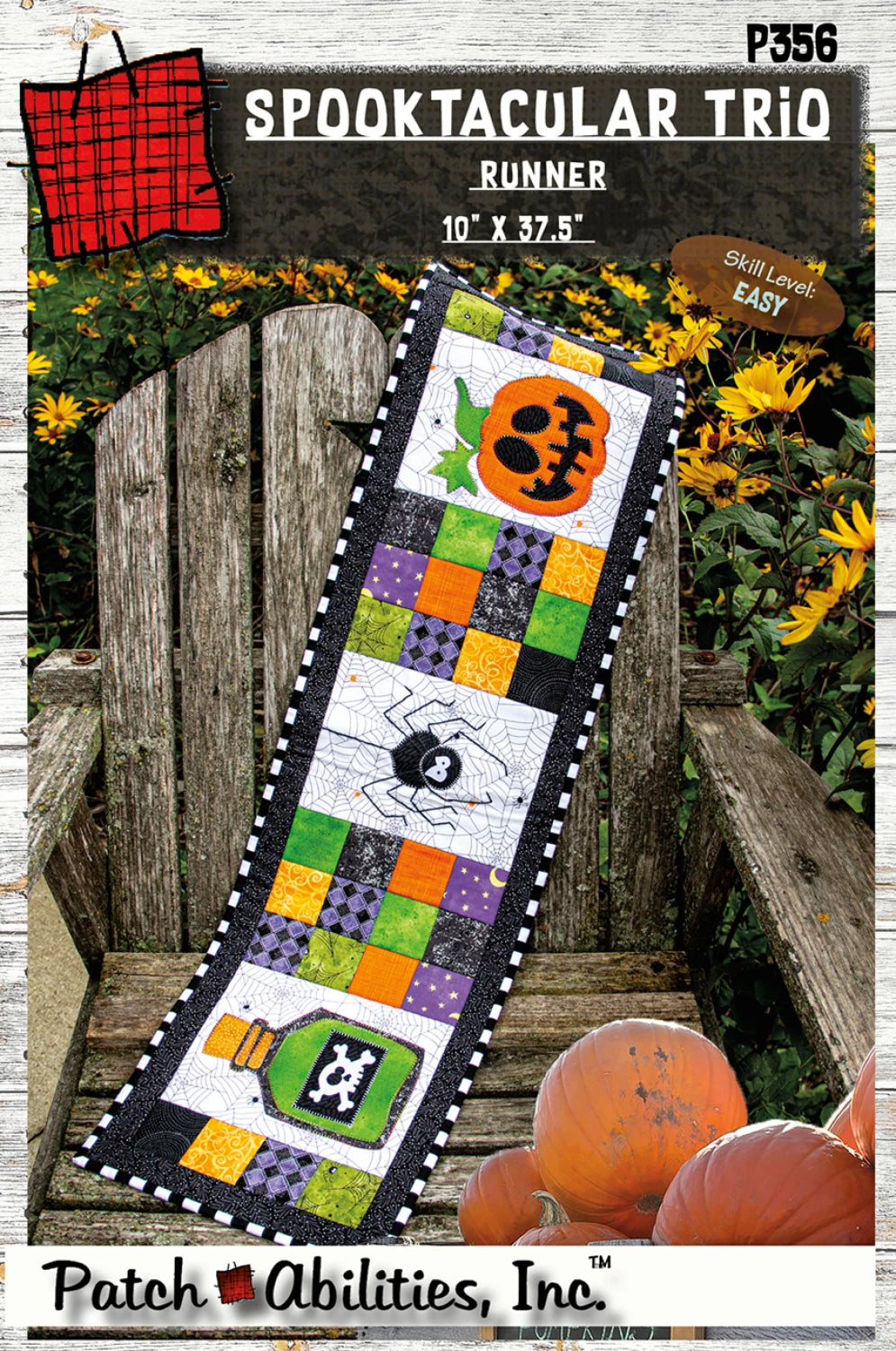 Halloween-themed quilt runner with pumpkins and spider design on a wooden bench with pumpkins.